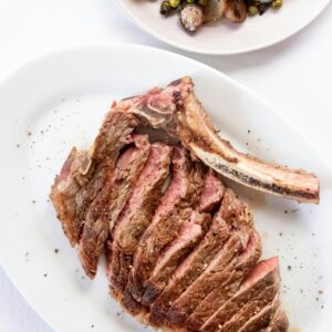 Top view composition of appetizing fresh ribeye steak cut on plate and served on table near mussel salad in fine restaurant